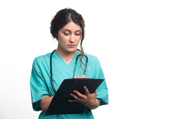 女性带听诊器的女医生在白色背景的剪贴板上写东西高质量的照片制服书写医生