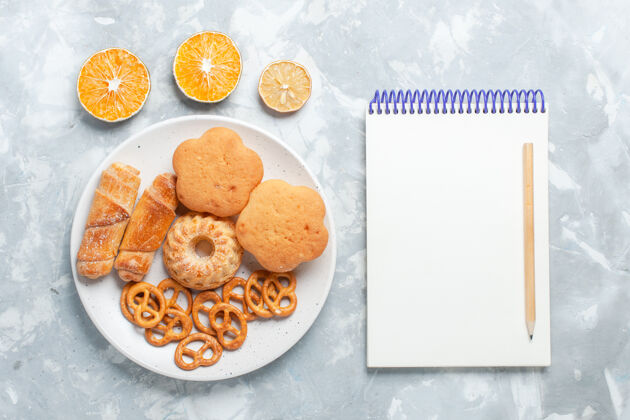 美味顶视图美味的百吉饼饼干饼干和蛋糕在盘子里在浅白色的桌子上烘焙茶饼干
