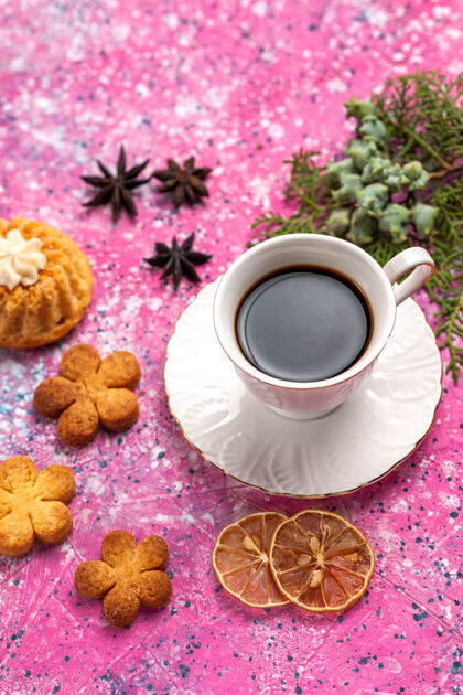食物在浅粉色的桌子上放上一杯茶 上面放着小蛋糕和饼干茶碟茶蛋糕