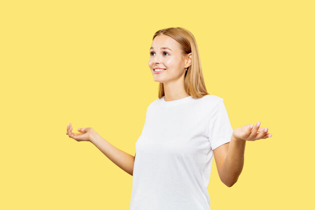 专业黄色工作室背景上的白人年轻女子半身像穿着白衬衫的漂亮女模特人类情感的概念 面部表情展示一个空酒吧和微笑面部金发公司