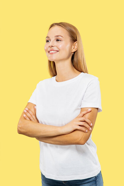 工作黄色工作室背景上的白人年轻女子半身像穿着白衬衫的漂亮女模特人类情感的概念 面部表情 销售双手交叉站立 自信女性人职业