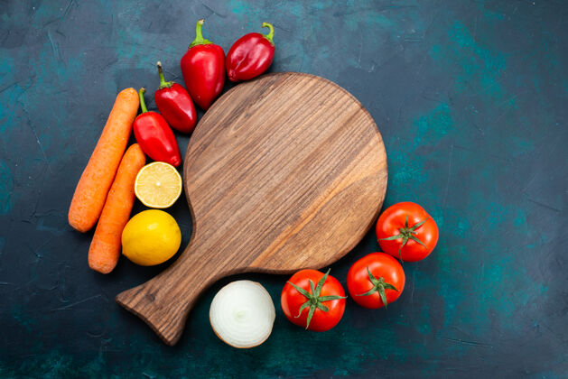蔬菜在深蓝色的桌子上俯瞰新鲜的红色西红柿和柠檬胡萝卜和胡椒红色番茄深蓝色
