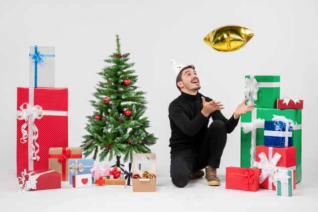 礼物年轻人围坐在礼物旁边 把金星雕像扔在白墙上人庆祝圣诞快乐