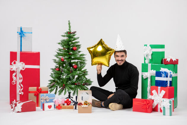 节日年轻人围坐在礼物旁边 拿着金星在白色的墙上礼物装饰圣诞快乐