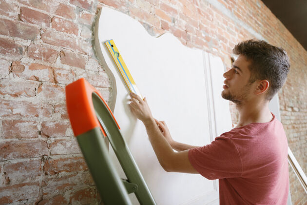 男性年轻人准备自己动手修缮公寓在家庭改造或翻新之前关系 家庭 diy的概念在绘画或设计之前测量墙壁测量测量搬家