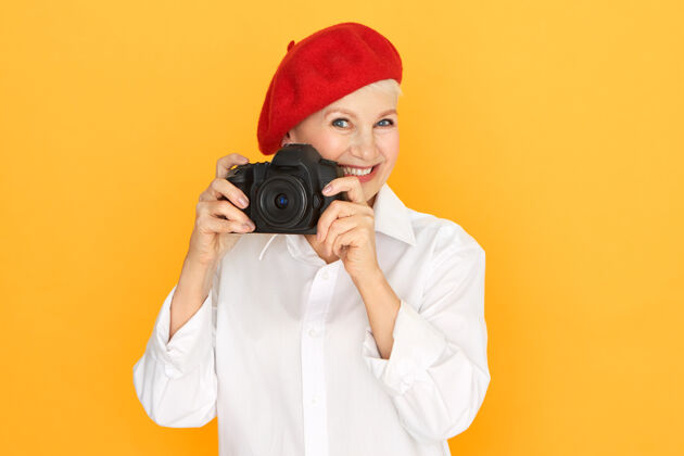女性人 老龄化 退休和创造性的职业概念高级女摄影师的肖像在白色衬衫和红色帽子举行全画幅单反相机设备成熟成人