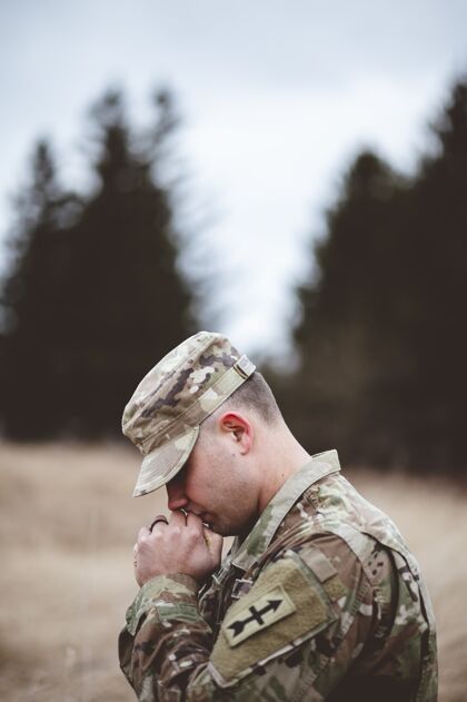 防御者一个年轻士兵在野外祈祷的浅焦垂直镜头浅国家军队
