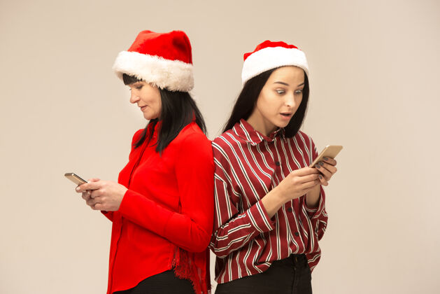 微笑穿着圣诞毛衣和手机合影的快乐家庭享受爱的拥抱 度假的人们在工作室里灰色背景上的妈妈和道格特孩子妈妈家庭