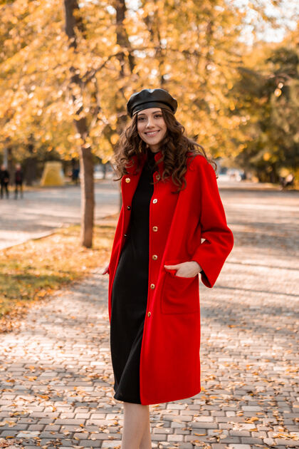秋天迷人的时尚微笑的女人卷发漫步在公园穿着温暖的红色外套秋季时尚 街头风格 戴贝雷帽女士摆姿势时尚