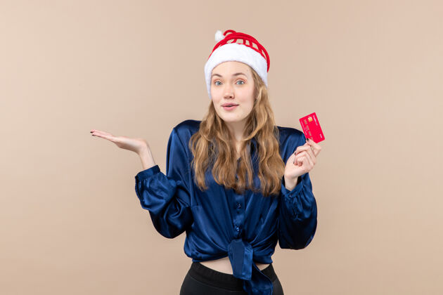 抱着正面图年轻女性手持粉色背景的红色银行卡圣诞钱照片节日新年感慨情感肖像女性