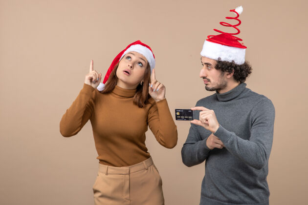 红色圣诞心情激动满意酷情侣戴红色圣诞老人帽伙计出示银行卡灰色显示酷