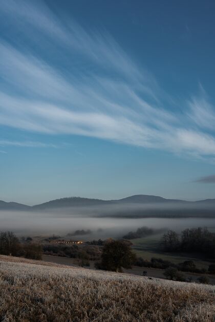 云垂直拍摄一片雾蒙蒙的田野和群山 背景是蓝天山森林景观