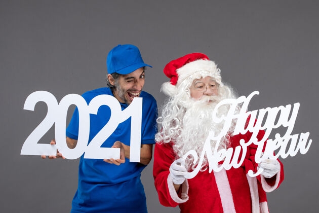 前面圣诞老人与男信使举行和新年快乐和2021年板灰墙的正面视图圣诞老人庆祝圣诞老人