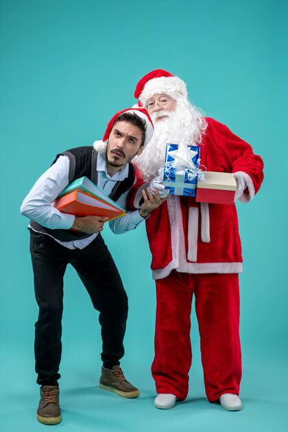圣诞老人前视图圣诞老人与年轻的男性和礼物在蓝色地板寒冷的圣诞节假期雪新年视图年轻人礼物