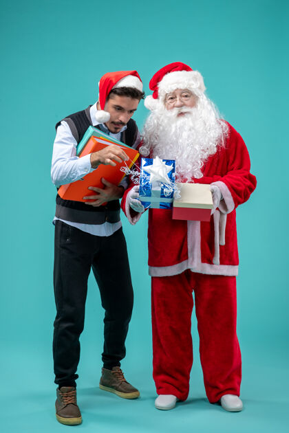 圣诞老人前视图圣诞老人与年轻的男性和礼物上的蓝色背景视图礼物男性