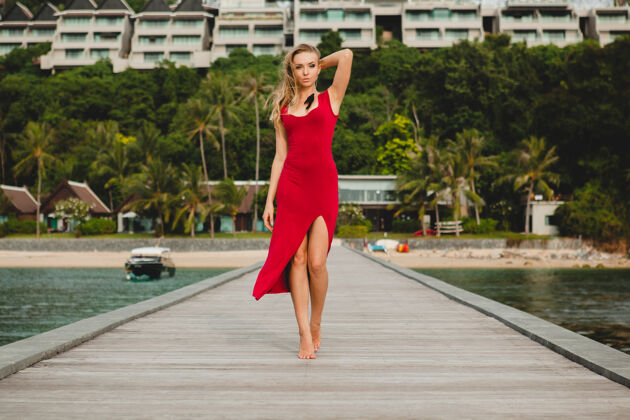 度假胜地年轻漂亮迷人的女人独自站在豪华度假酒店的码头上 暑假 红色长裙 金色头发 性感服装 热带沙滩 诱惑 性感 微笑女性放松优雅