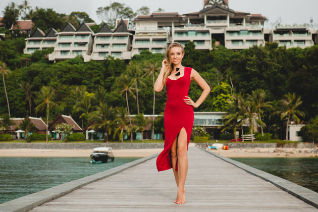 奢华年轻漂亮迷人的女人独自站在豪华度假酒店的码头上 暑假 红色长裙 金色头发 性感服装 热带沙滩 诱惑 性感 微笑岛屿女孩海洋