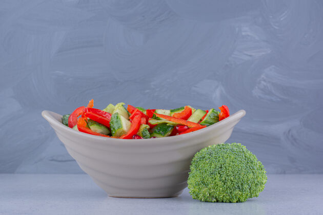 碗一碗沙拉 旁边是大理石背景上的一片西兰花沙拉美味蔬菜
