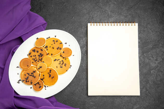 薯条在黑暗的背景上俯瞰美味的巧克力薄饼好吃的薄煎饼笔记本甜点