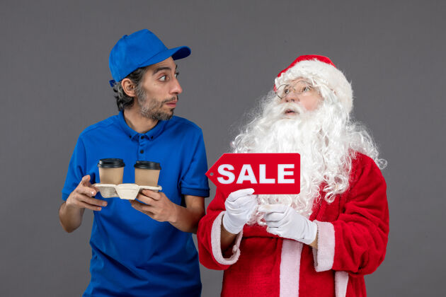 节日圣诞老人的正面图 男信使拿着售货笔 灰色墙上挂着咖啡人举行服装