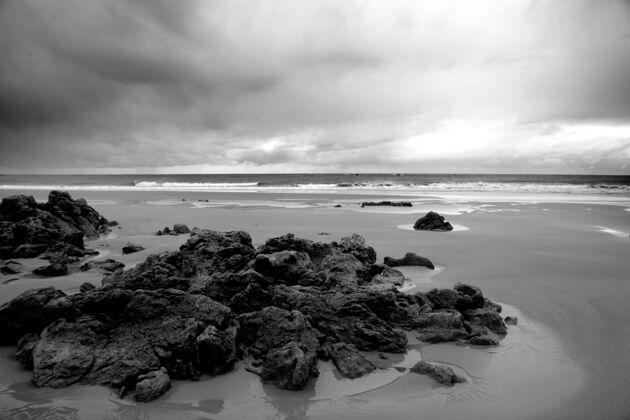 海岸在白天多云的天空下 灰色的海滩被岩石和波浪包围自然热带白天