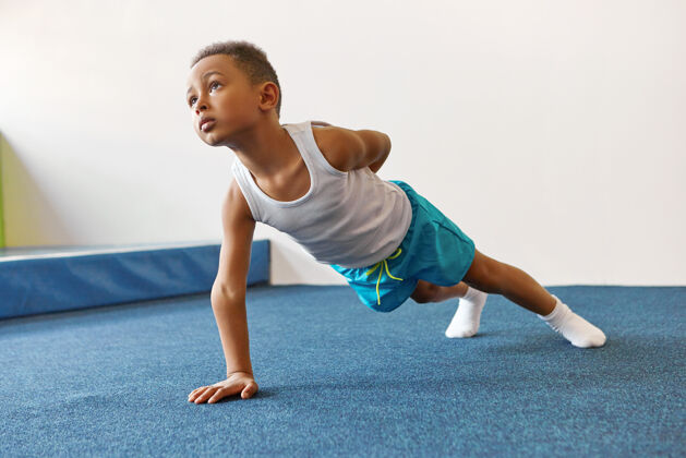 身体穿着运动服 守纪律的瘦骨嶙峋的非洲裔美国孩子在做单臂板运动男孩帅气