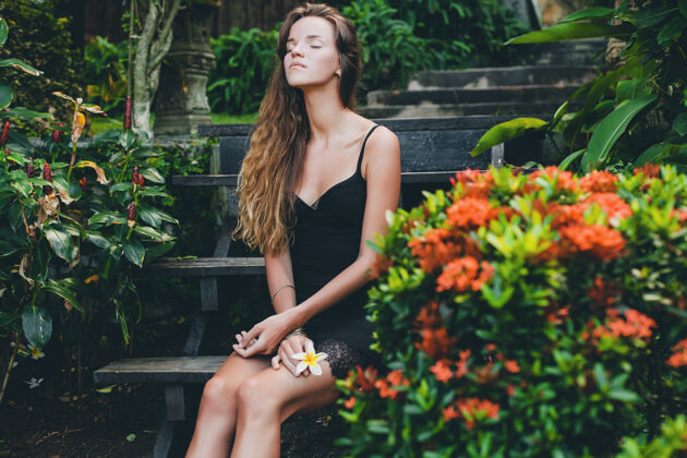 漂亮热带花园里年轻漂亮性感的女人 在泰国度暑假 苗条瘦削的棕褐色身材 带蕾丝的小黑裙 自然的造型 感性的 放松的 温柔晒黑感性
