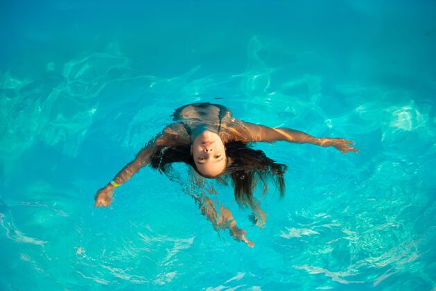 夏天在一个温暖的热带国家度假期间 阳光明媚的夏夜 俯瞰图女孩少年在温暖清澈的蓝色水中游泳概念恢复和娱乐休闲游泳池快乐