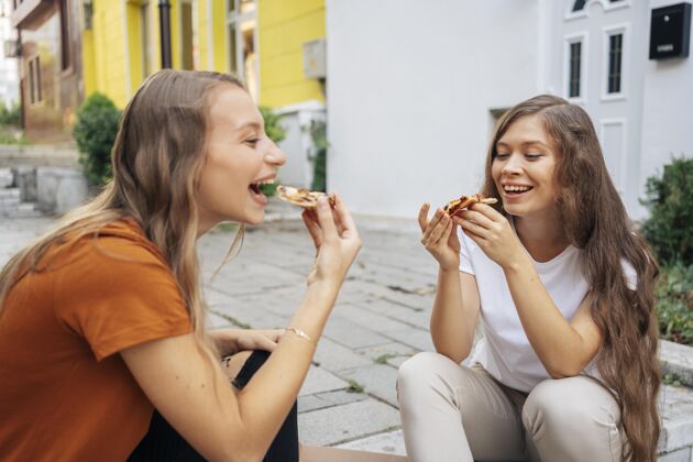 娱乐年轻女人一起在户外吃披萨快乐年轻朋友