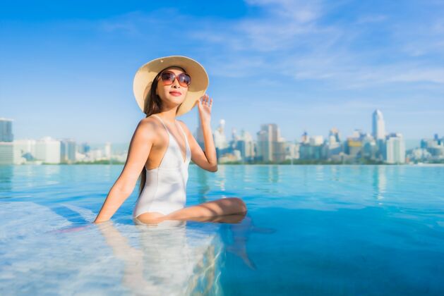 屋顶美丽的亚洲年轻女子在户外游泳池周围放松 城市景色尽收眼底城市景观酒店城市