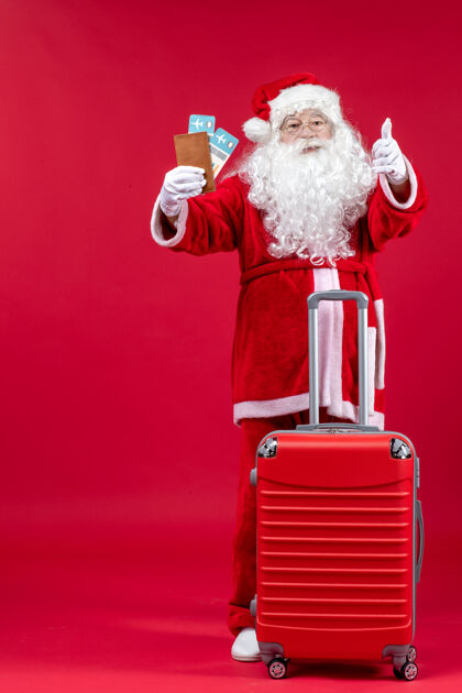旅行圣诞老人的前视图 带着包 拿着票 准备在红墙上旅行圣诞快乐假期圣诞老人