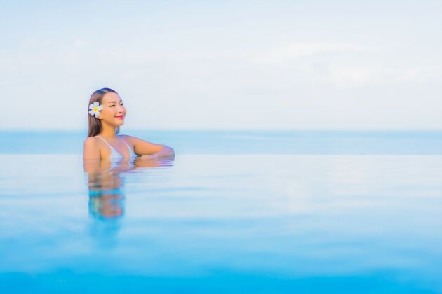 性感肖像美丽的亚洲年轻女子放松微笑周围的室外游泳池在酒店度假村海洋亚洲人豪华