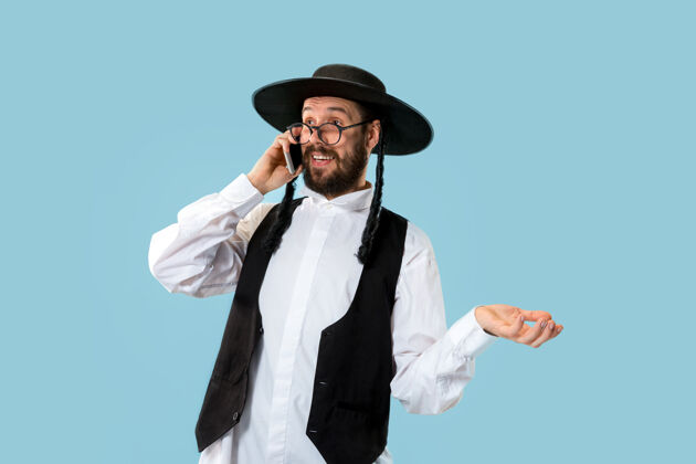 帽子一个年轻的东正教犹太男子的肖像和手机在工作室胡须传统节日
