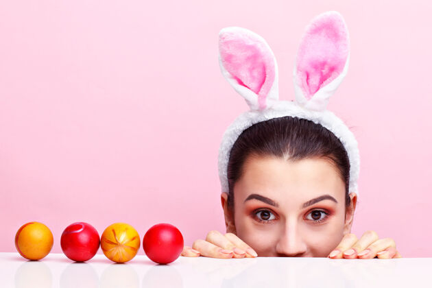 眼睛戴着兔子耳朵吃复活节彩蛋的快乐的年轻女人耳朵传统乐趣