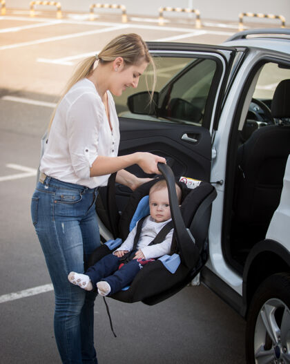 汽车年轻母亲与婴儿一起安装汽车儿童座椅的画像年轻人小孩车辆