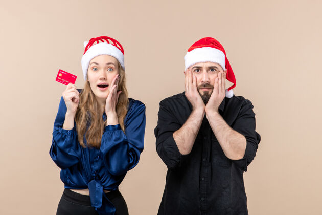 人一个年轻人和一个拿着银行卡的女人在粉色墙上的正视图女性圣诞快乐情感