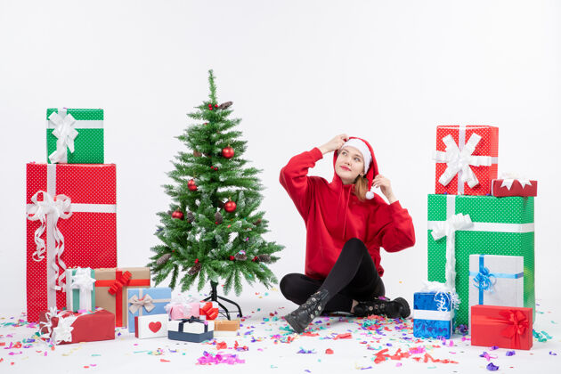 节日年轻女子围坐在白墙上的礼物面前情感圣诞快乐十二月