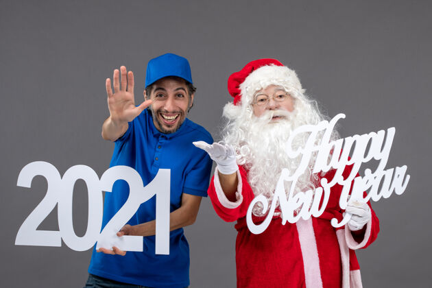 肖像圣诞老人与男信使举行和新年快乐和2021年板灰墙的正面视图快乐信使帽子