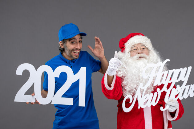 前面圣诞老人与男信使举行和新年快乐和2021年板灰墙的正面视图男信使肖像