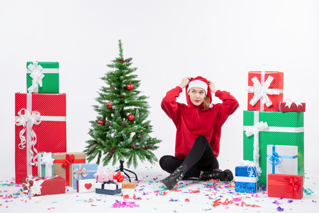 十二月年轻女子围坐在白墙上的礼物面前礼物节日坐着