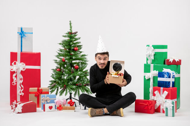 人正面图：年轻人围坐在白色的墙上 手里拿着圣诞礼物前面庆祝礼物