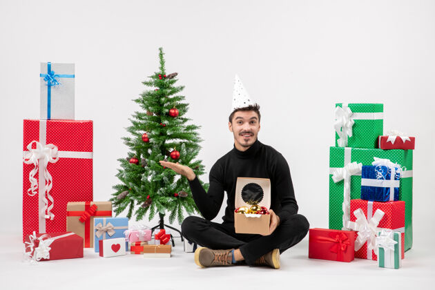 快乐年轻人围坐在白墙上的礼物面前礼物圣诞快乐人