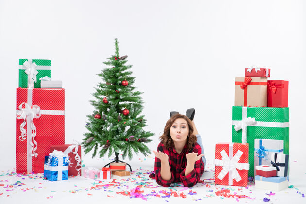 礼物正面图年轻女性躺在白色背景上的圣诞礼物和圣诞树上圣诞新年礼物颜色雪白周围礼物雪