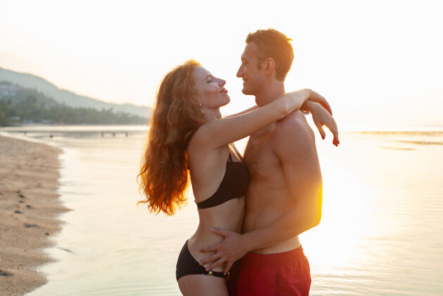 情人年轻性感浪漫的情侣在夏天的沙滩上快乐地穿着泳装玩情侣乐趣蜜月