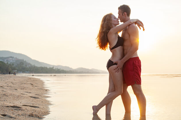 海岸年轻性感浪漫的情侣在夏天的沙滩上快乐地穿着泳装玩男人男性乐趣