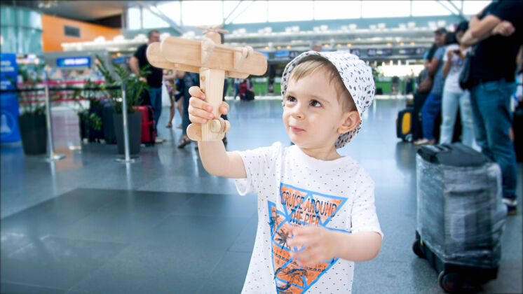 等待可爱的蹒跚学步的男孩在机场候机楼玩玩具飞机的画像喷气机人婴儿