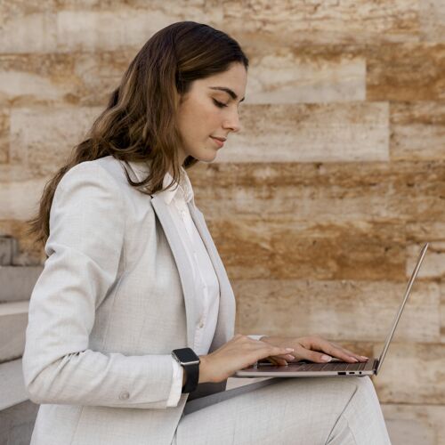 优雅侧视图优雅的女商人与智能手表工作在笔记本电脑户外精致女士优雅