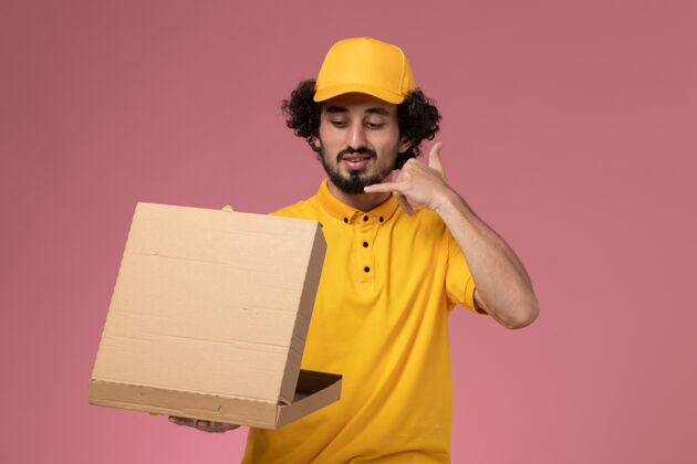 工作正面图男快递员穿着黄色制服拿着食品快递箱放在浅粉色的办公桌上工作公司制服服务快递男男送货正面