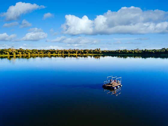 航海摩托艇在湖面上环绕着美丽的绿树 天空阴云密布蓝色阳光摩托艇