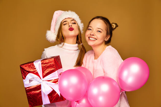 时尚圣诞节带着大礼盒和粉色气球的模特们青少年庆祝圣诞老人